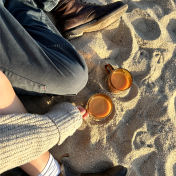 Drinks and legs sitting in sand