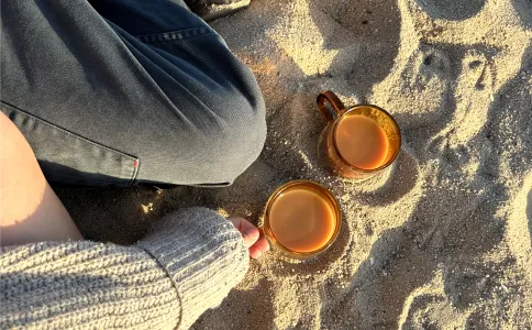 Drinks and legs sitting in sand