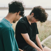 Two male friends laughing at beach sitting